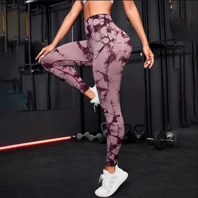 Woman wearing seamless high waist gym leggings with purple tie-dye pattern in a gym setting