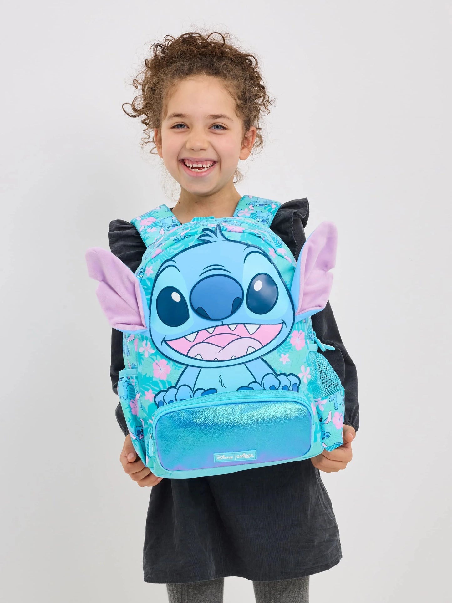 Smiling girl wearing a turquoise character backpack with plush ears Smiggle school bag set for girls.