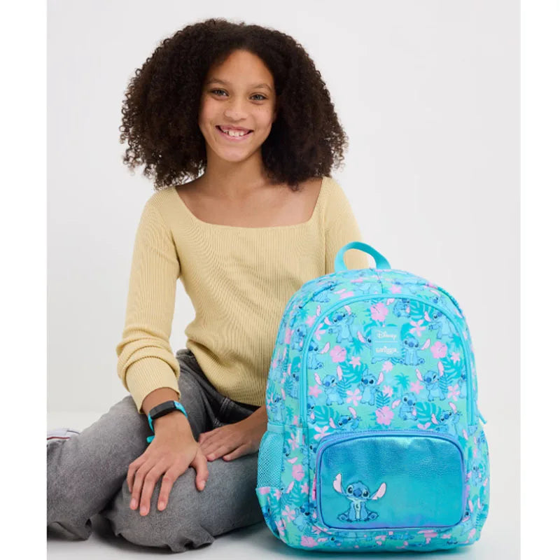 Smiling girl sitting beside a turquoise Stitch print backpack with mesh pockets Smiggle school bag set for girls