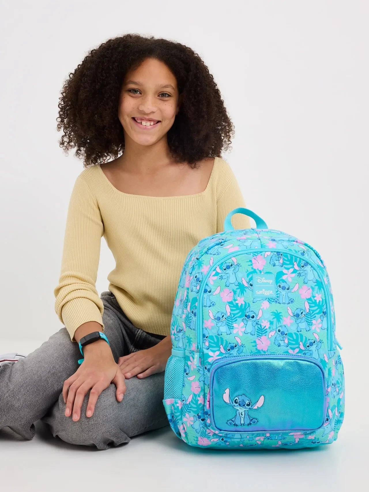 Smiggle school bag set for girls turquoise floral backpack with Disney Stitch front pocket shown with smiling girl