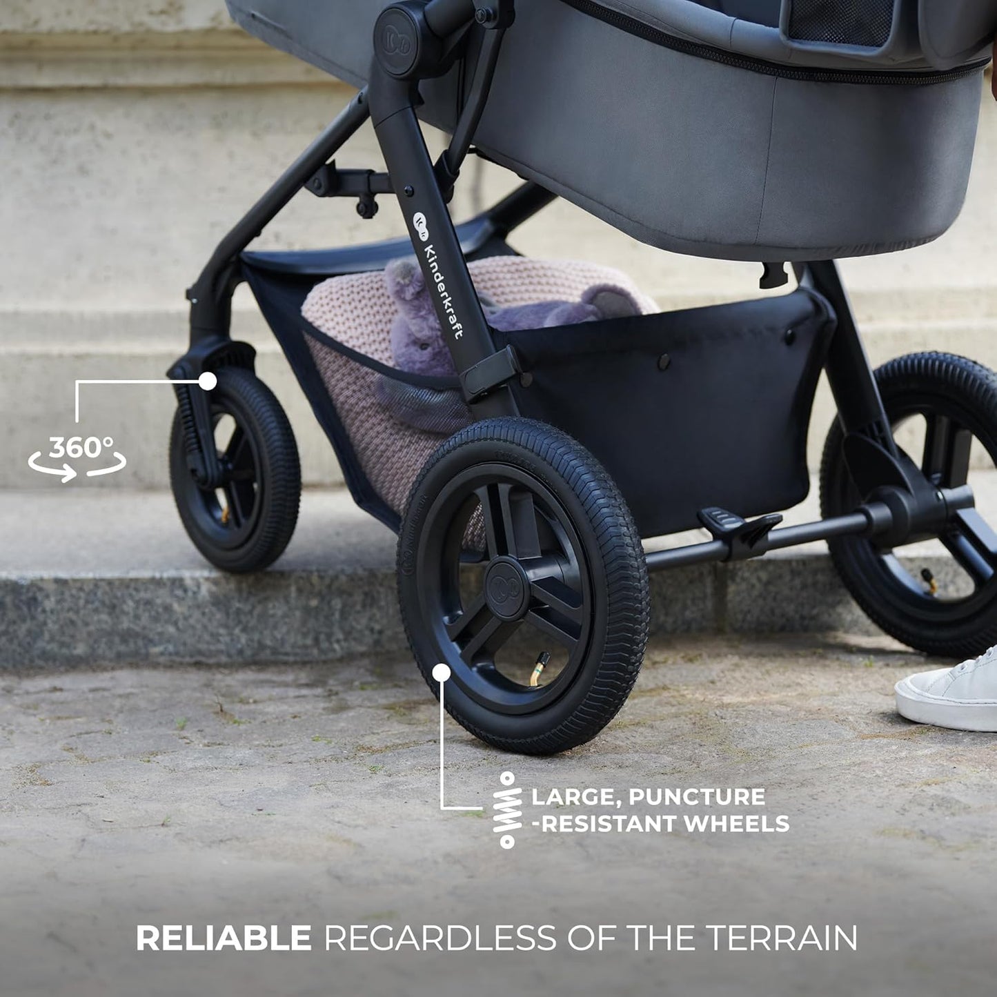 Black Kinderkraft MOOV2 AIR pram set showing large puncture resistant wheels and underseat basket with blanket
