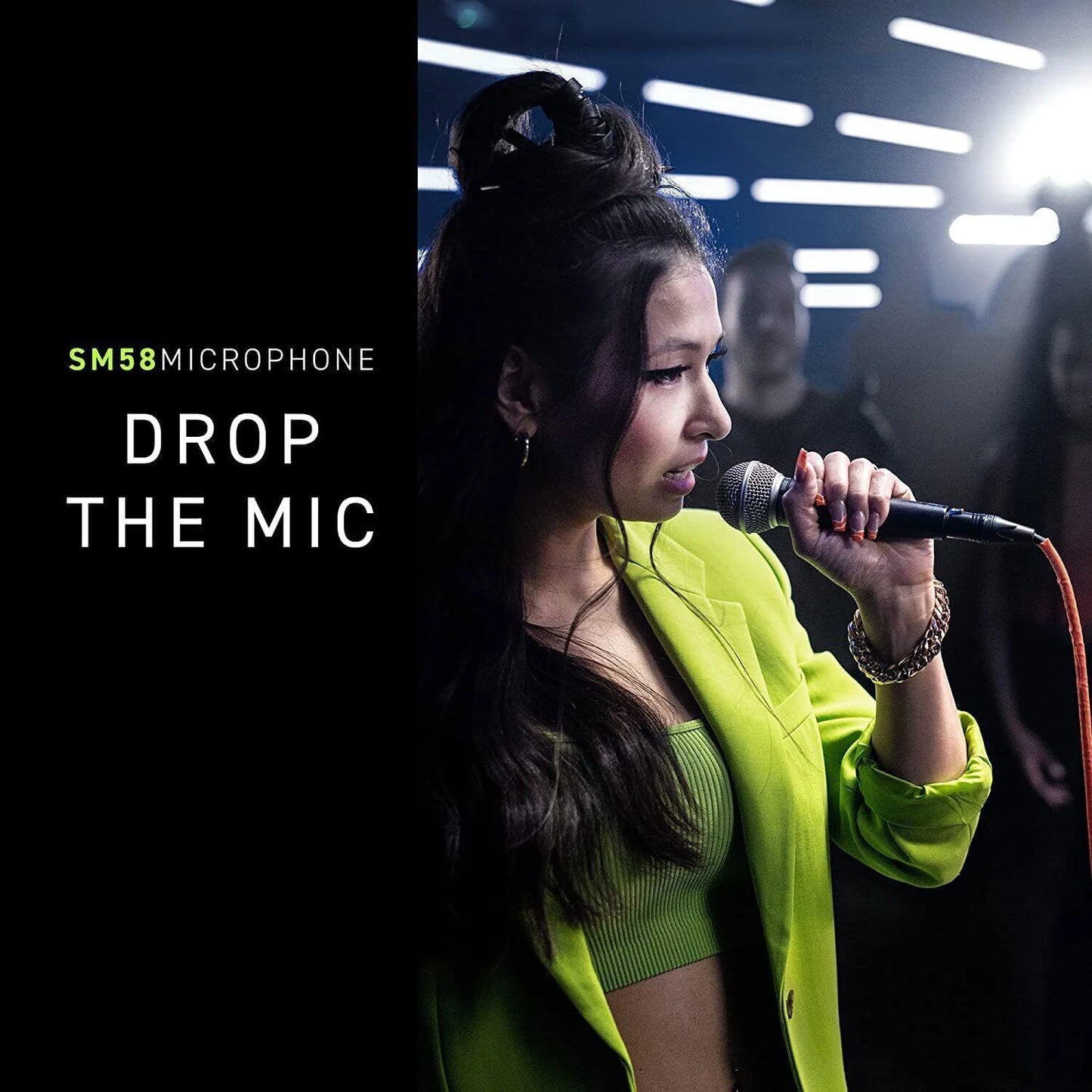 Female singer in neon green jacket performing on stage holding SM58 dynamic vocal microphone with cable