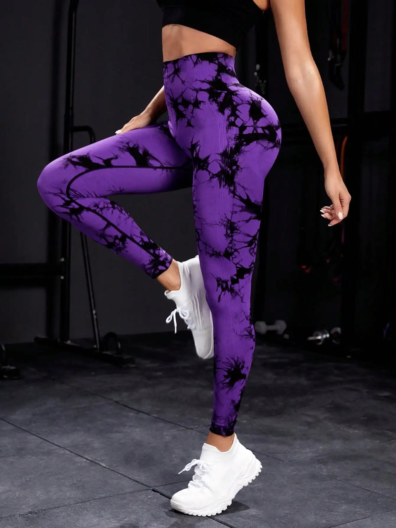 Purple and black tie-dye seamless high waist gym leggings worn with white trainers in gym setting