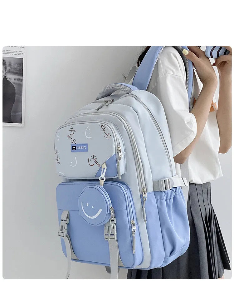Light blue and white primary school backpack for girls with multiple zip compartments padded straps and smiley front pouch