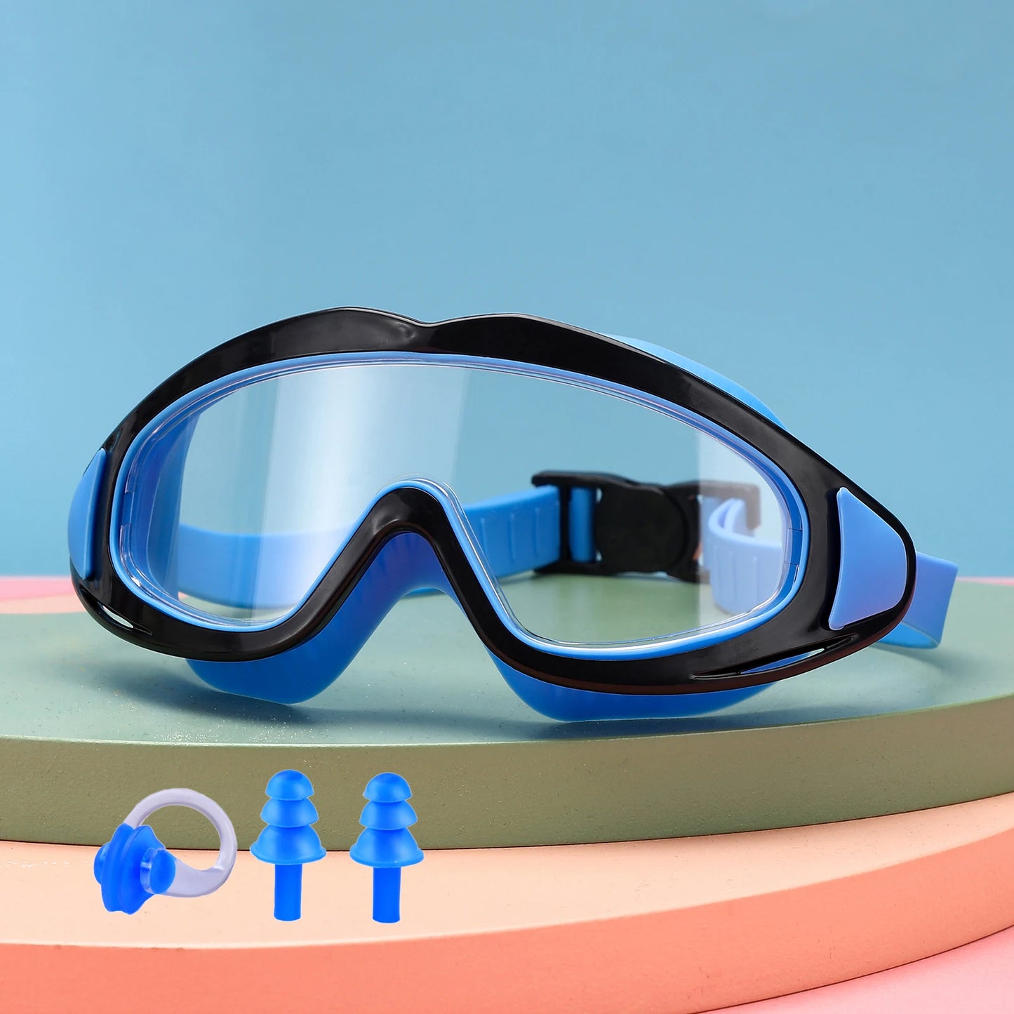 Blue and black UV protection kids pool goggles with adjustable strap and earplugs on pastel background