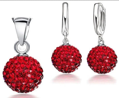 Silver jewelry set with red gemstones on a white background