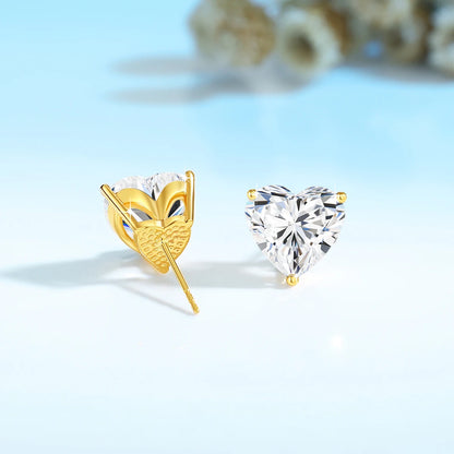 Gold and clear heart-shaped earrings on a light blue background