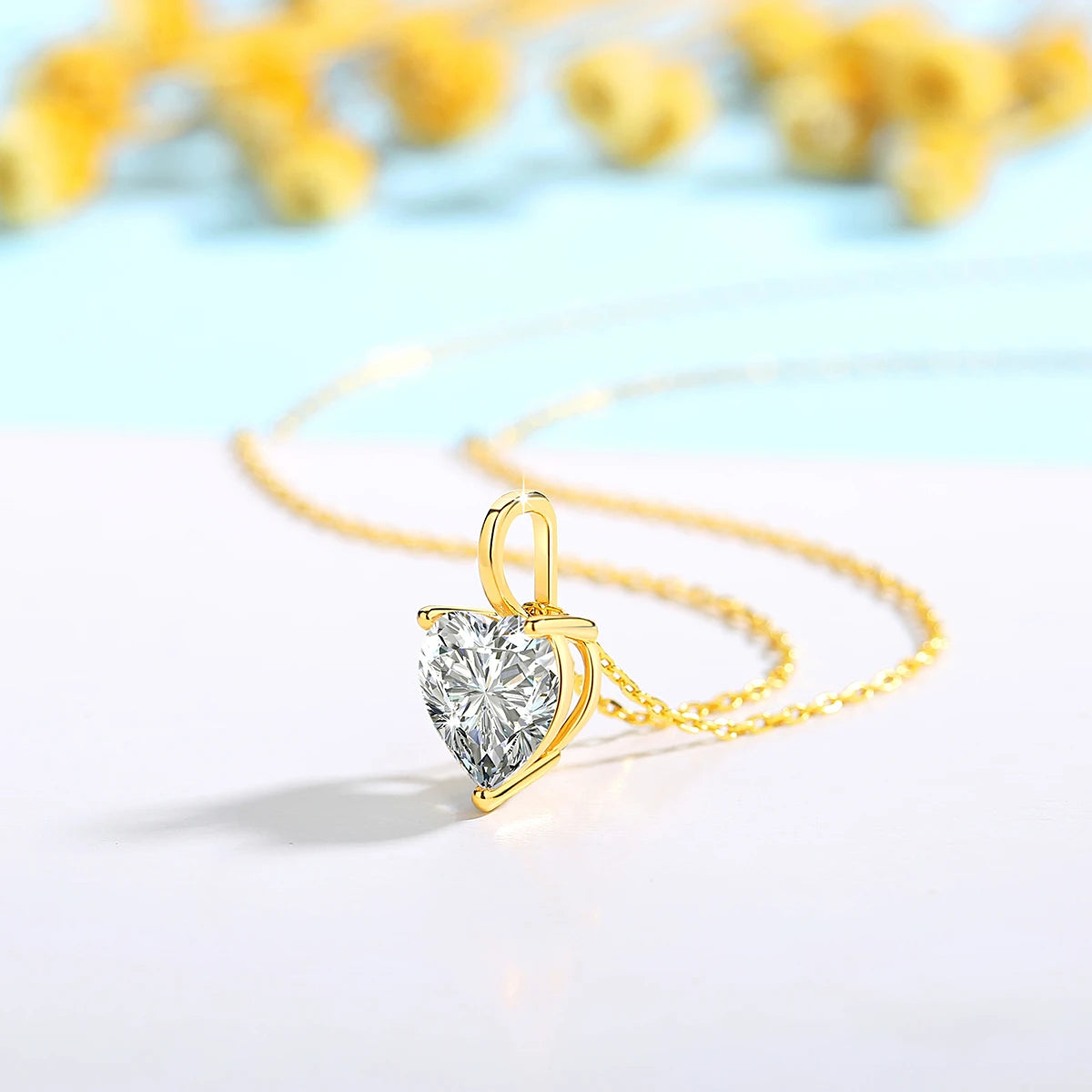 Gold necklace with a heart-shaped diamond pendant on a light blue background