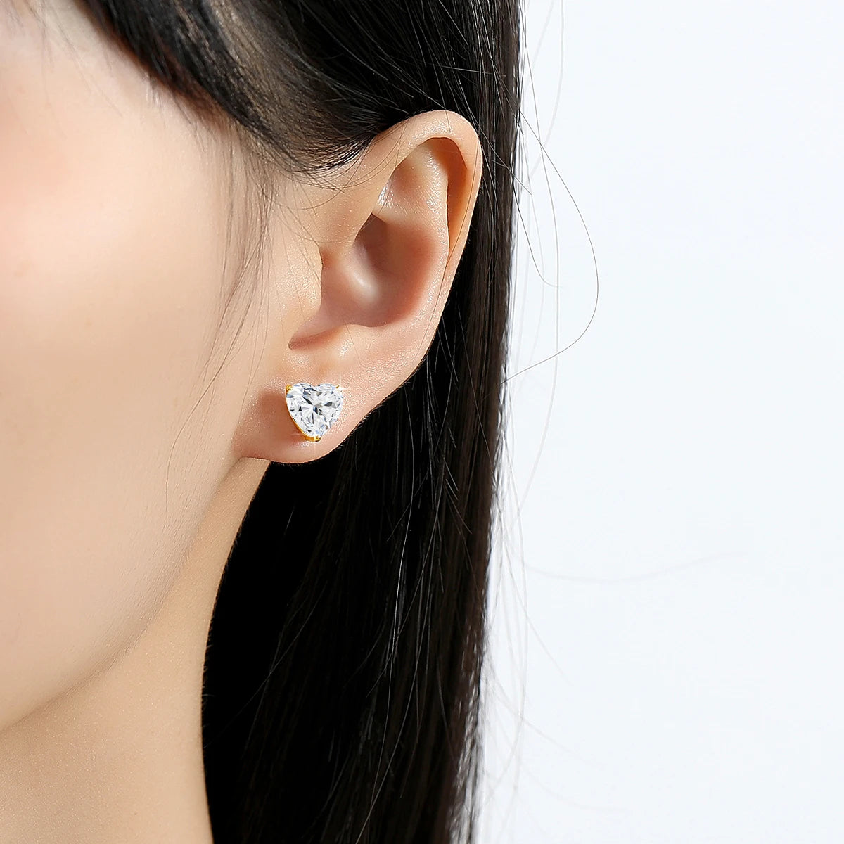 Heart-shaped diamond earring worn by a model on a white background