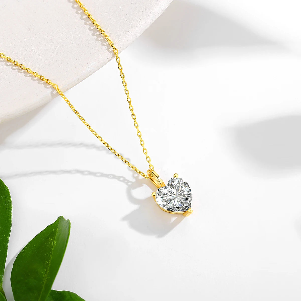 Gold necklace with a heart-shaped diamond pendant on a white background