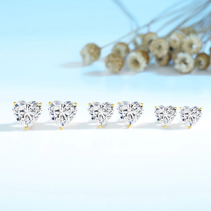 Heart-shaped diamond earrings on a light blue background with dried flowers.