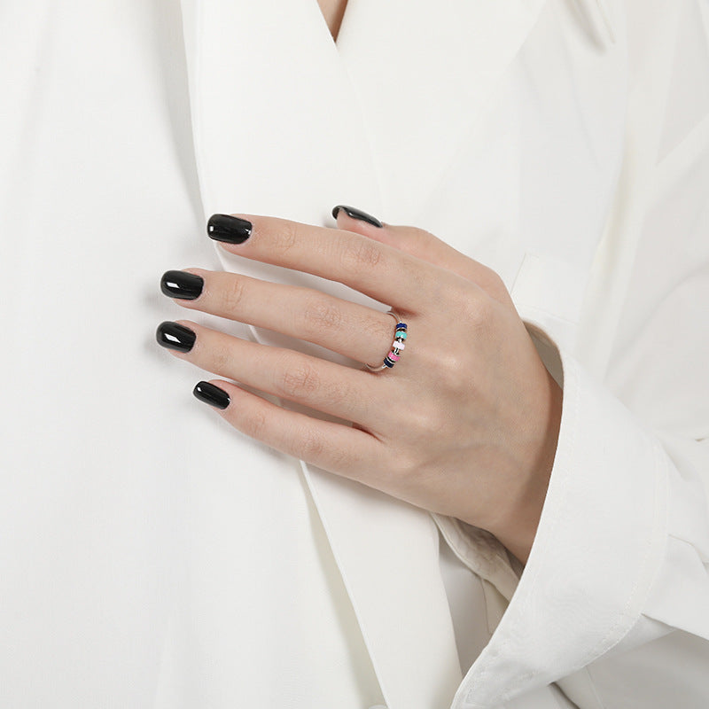 Model hand with black nails wearing European Style Drip Oil Ring multicolour gemstone band on white blouse