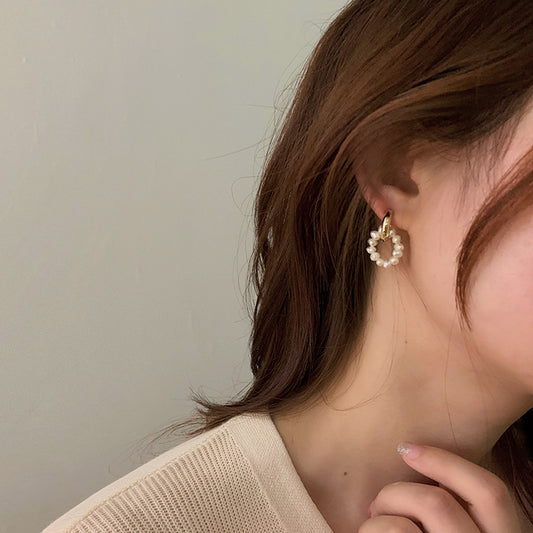 Close up of eprolo French buckle pearl earrings for women gold hoop with small pearls worn by model