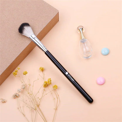 DUcare highlighter brush with soft bristles placed next to a flower, a glass bottle, and colourful candies