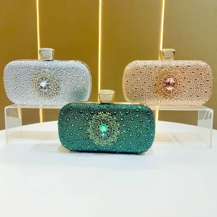 Three elegant handbags including an emerald rhinestone party handbag showcased on a display