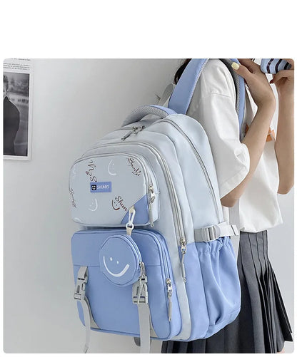 Light blue and white primary school backpack for girls with multiple zip compartments padded straps and smiley front pouch