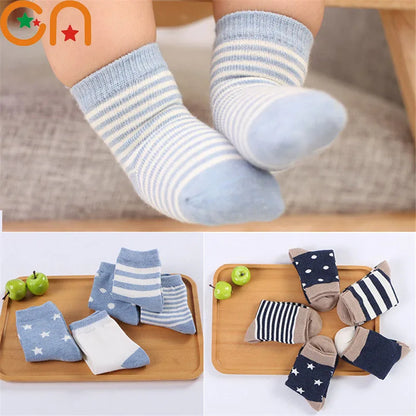 Soft toddler socks for boys and girls in various colours and patterns on a wooden tray