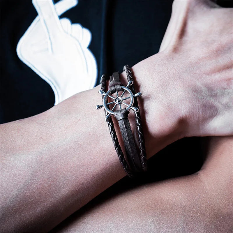 Vintage braided leather charm bracelet with a decorative ship's wheel detail, worn on a wrist